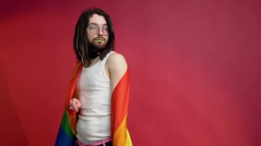 Kırmızı arka planda gökkuşağı bayrağı taşıyan adam. Gay gurur konsepti. Homoseksüel aşka oy verin