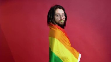 Kırmızı arka planda gökkuşağı bayrağı taşıyan adam. Gay gurur konsepti. Homoseksüel aşka oy verin.