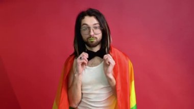 Kırmızı arka planda gökkuşağı bayrağı taşıyan adam. Gay gurur konsepti