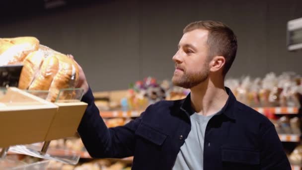 シニアマン食品を選ぶ スーパーマーケットの棚から食品を選ぶ パン屋 食料品店 — ストック動画