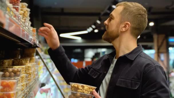 スーパーでナッツとドライフルーツを選ぶ男 — ストック動画