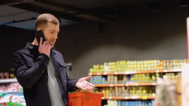 Süpermarkette brokoli seçen genç bir adam. Süpermarketteki raftan yiyecek seçmek.