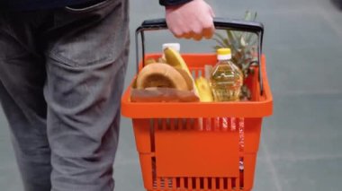 Alışveriş sepeti olan bir adam süpermarkette yürür. Süpermarkette doğru ürünü seçen bir adam