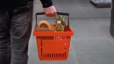 Alışveriş sepeti olan bir adam süpermarkette yürür. Süpermarkette doğru ürünü seçen bir adam.