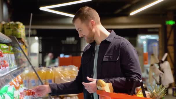 スーパーでトマトを選んでいる若者 スーパーマーケットの棚から食品を選ぶ — ストック動画