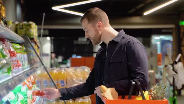 スーパーでトマトを選んでいる若者 スーパーマーケットの棚から食品を選ぶ — ストック動画