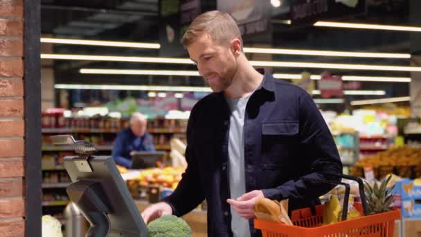 消费主义和人的观念 在杂货店大规模称重西兰花的年轻人 — 图库视频影像