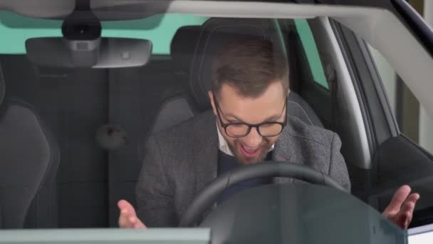 Szczęśliwy Człowiek Siedzi Nowym Samochodzie Elektrycznym Salonie Sklepowym Świętować Zakup — Wideo stockowe