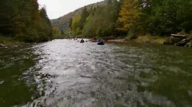 Mavi şişme kanolardaki mutlu, hayalperest erkekler bir nehrin sakin sularında eğlenceli bir gezinti yapıyorlar..