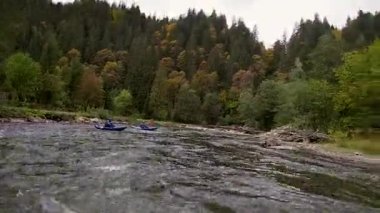 Mavi şişme kanolardaki mutlu, hayalperest erkekler bir nehrin sakin sularında eğlenceli bir gezinti yapıyorlar.