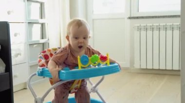 First steps of the girl in a baby walker. Childhood concept