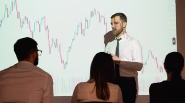 Young trader presents cryptocurrency investment strategy for group of investors on candlestick chart