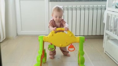 Cute baby with toy walker at home. Childhood concept