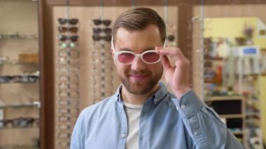 Young man choosing retro oval sunglasses in Kurt Cobain style