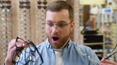 Portrait of handsome bearded guy picking new specs at optical shop. Choosing glasses concept
