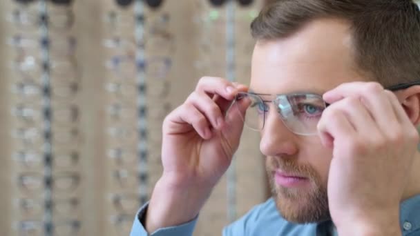 鏡を見て 光学店で新しい仕様を選ぶハンサムな髭の男の肖像画 メガネのコンセプトを選ぶ — ストック動画