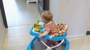 First steps of the girl in a baby walker. Childhood concept