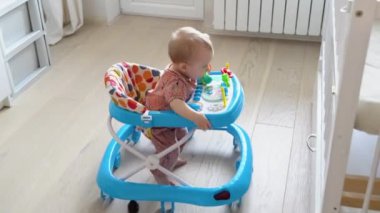 First steps of the girl in a baby walker. Childhood concept