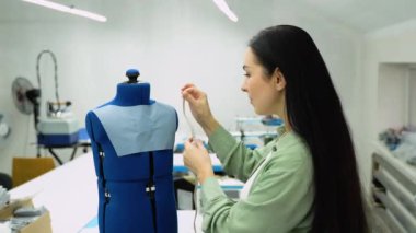Female dressmaker measures fabric on mannequin. Creating dress design. Tailor industry concept