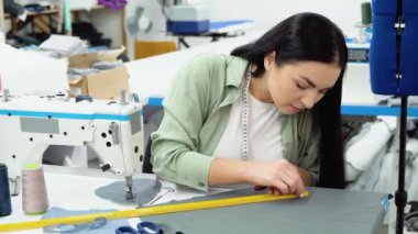 Focused nice brunette girl seamstress writing while working in factory