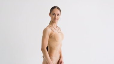 Beautiful young woman dressed in a beige sports uniform, posing in the studio on a white background. Healthy lifestyle, sport