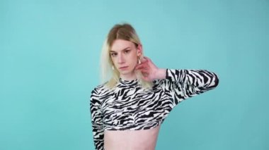 Young transvestite poses in studio on a blue background.