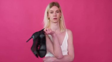 Transgender man with shoes on a pink background
