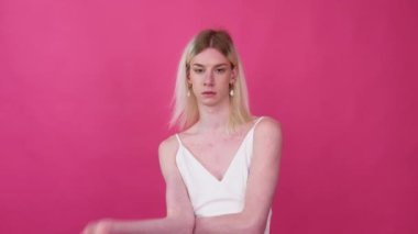 Transgender man with shoes on a pink background