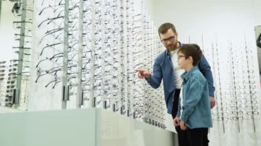 Family buy glasses. Father and son in a blue shirts choosing glasses.