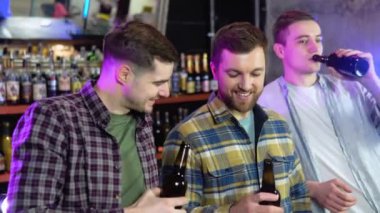Bir grup mutlu çok ırklı arkadaş birlikte eğleniyor, bir barda ya da evde şişe bira içiyor, kutlama yapıyor, mutlu bir şekilde gülümsüyor - arkadaşlık, birliktelik konsepti 4k çekim