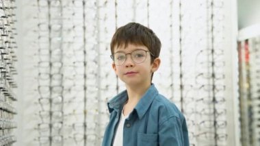 Little boy in optics store choosing glasses. Ophthalmology concept