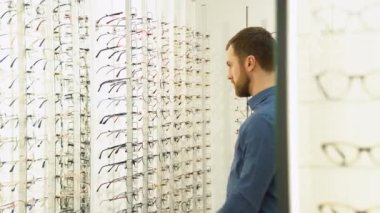 Health care, eyesight and vision concept - a man choosing glasses at optics store.