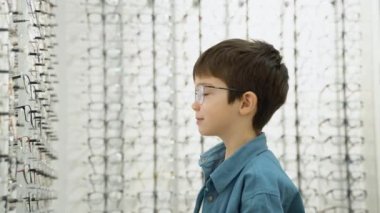 Little boy in optics store choosing glasses. Ophthalmology concept