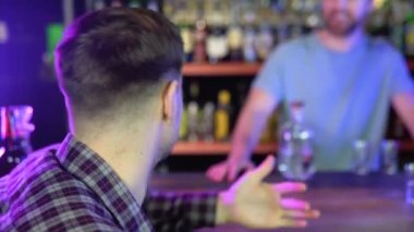 Male customer stand near counter talk with barista or waiter, millennial man client speak with barmen make order in bar or restaurant, place manager have conversation with staff