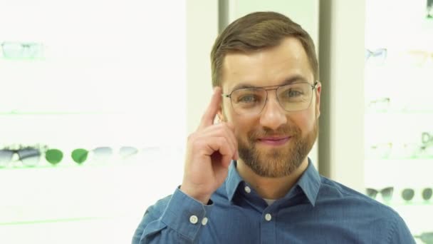 Happy Young Male Client Puts New Glasses Rack Showcase Eyewear — Vídeo de stock