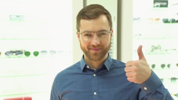 Happy Young Male Client Puts New Glasses Rack Showcase Eyewear — Vídeo de Stock