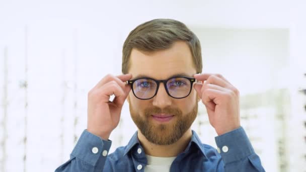 Happy Young Male Client Puts New Glasses Rack Showcase Eyewear — стоковое видео