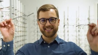 Health care, eyesight and vision concept - happy man choosing glasses at optics store.