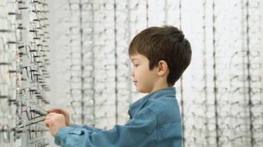 Little boy in optics store choosing glasses. Ophthalmology concept