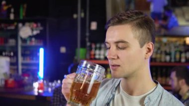 Portrait of a handsome caucasian young man drinking tasty golden refreshing beer beverage in a pub.