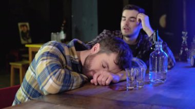 Two very drunken men are sitting in a bar