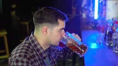 Portrait of a handsome caucasian young man drinking tasty golden refreshing beer beverage in a pub.