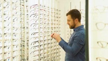 Health care, eyesight and vision concept - a man choosing glasses at optics store.