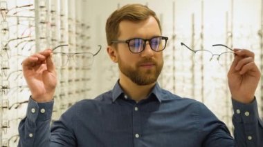 Health care, eyesight and vision concept - happy man choosing glasses at optics store.