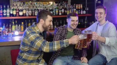Group of happy friends having fun together, drinking beer in a bar, celebrating, happily smiling - friendship, togetherness concept.