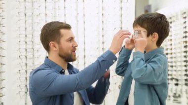 Family buy glasses. Father and son in a blue shirts choosing glasses.