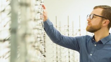 Health care, eyesight and vision concept - a man choosing glasses at optics store.