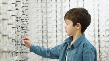 Little boy in optics store choosing glasses. Ophthalmology concept