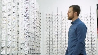 Health care, eyesight and vision concept - a man choosing glasses at optics store.