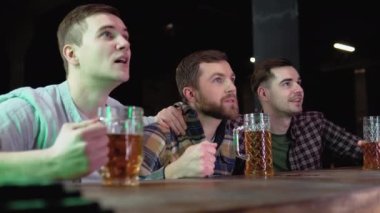 Loyal football fans supporting their team. Men cheering their team in the pub.